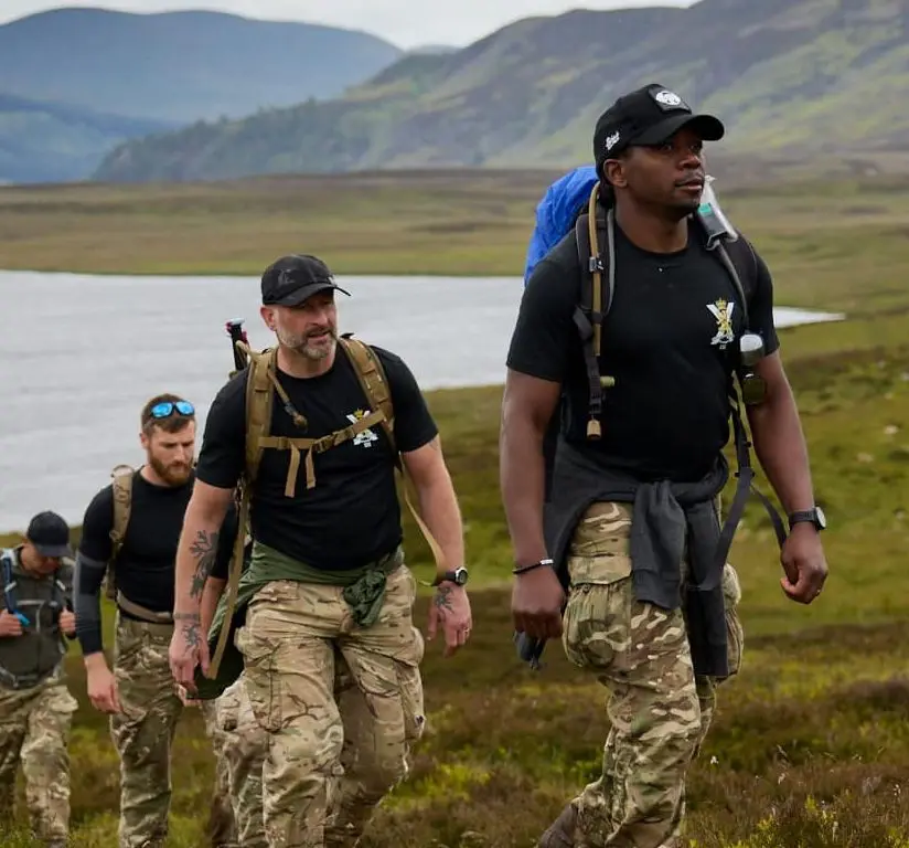 Team of walkers climbing up a hill with lake in the background as part of the Cateran Yomp