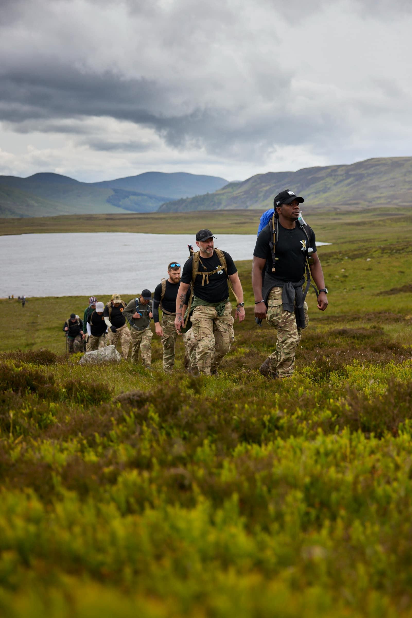 Team of walkers climbing up a hill with lake in the background as part of the Cateran Yomp